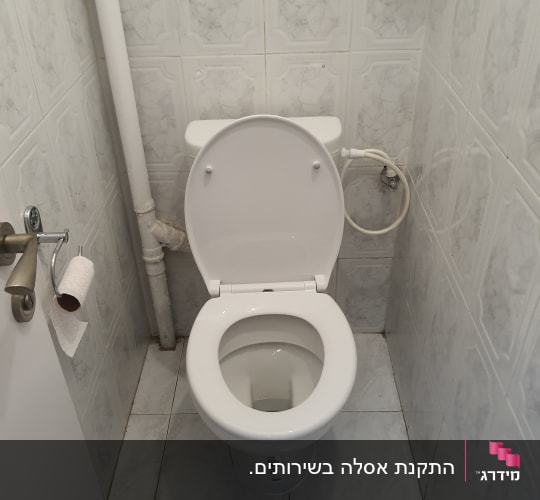 אסלה לבנה עם צינור מים מחובר לקיר